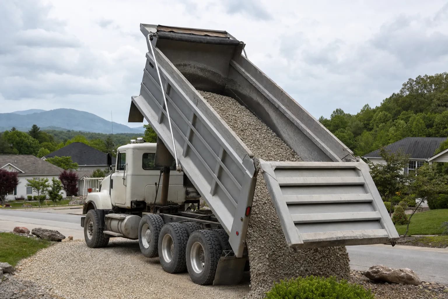 Dump truck delivering gravel to a residential property